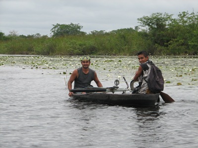Men paddling a dugout canou with a bicycle on the New River, Belize